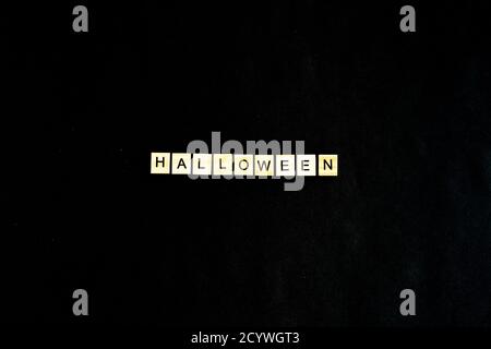 Words Halloween. Wooden blocks with lettering on black background decorated with pumpkins. Top view, flat lay. Happy Halloween Stock Photo
