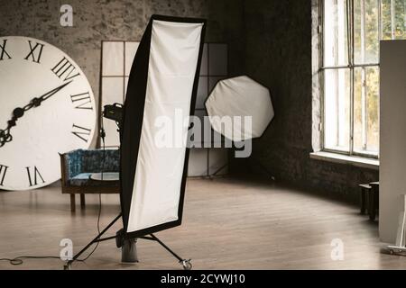 Studio light in a decorated photo studio. There's a big watch and a sofa in the background. Grey interior. High quality photo Stock Photo