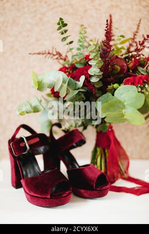 Burgundy suede platform sandals and high heels with a red bridal bouquet. Stock Photo
