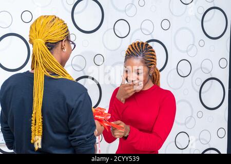 african lady receiving a gift from a friend feeling excited Stock Photo