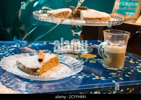The tasty homemade cinnamon cake with sugar, accompanied by a cup of fresh coffee with chocolate and some Tasty and healthy almond cookies, rich in vi Stock Photo
