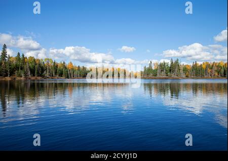 Blue lake with treeline in autumn color on a sunny afternoon in northern Minnesota Stock Photo