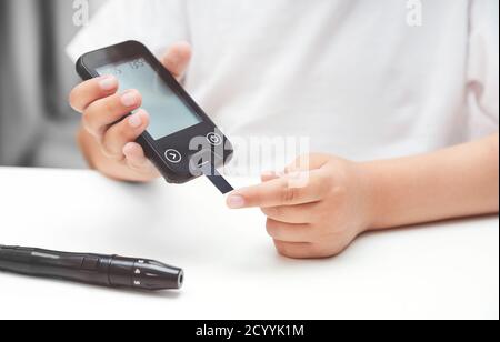 Young boy using glucometer, checking blood sugar level. Diabetes and children health care concept Stock Photo