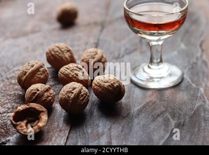 Walnut liquor in glass and walnuts on the old wooden background in backlight Stock Photo