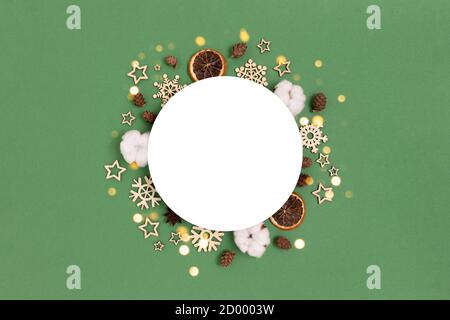 Round blank mockup with frame made of natural Christmas decoration on a green background. New Years concept with place for text. Stock Photo