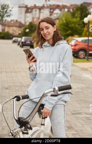 young woman cyclist posing with bike on the road smiling Stock Photo