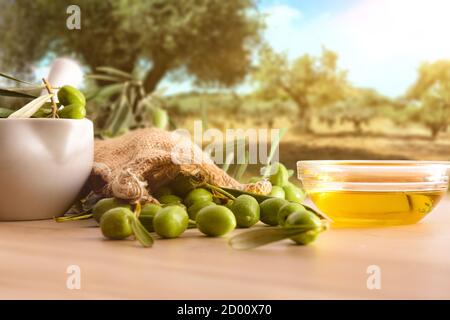 Preparation of olive oil seed in ceramic glass for body care on table with mortar and sack of olives in nature. Front view. Stock Photo