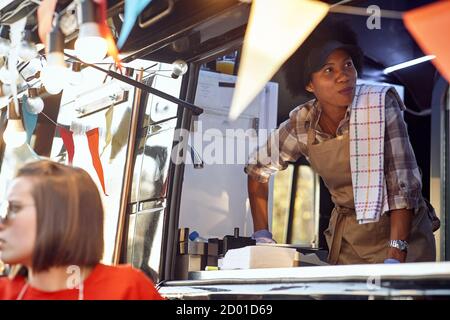 Afro american food truck employee taking orders from customers Stock Photo
