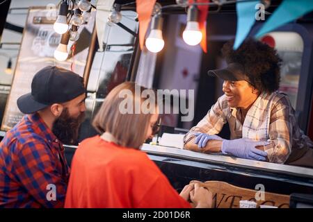 Afro american food truck employee taking orders from hipster customers Stock Photo