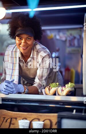Cheerful afro american food truck employee taking orders from customers Stock Photo