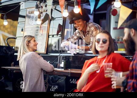 Afro american food truck employee taking orders from customers Stock Photo