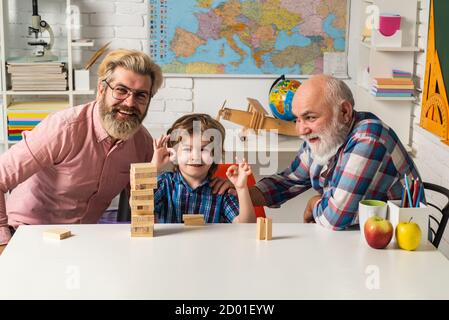 Grangfather, Father and son playing jenga game at home. Grandfather teaching grandson how to play Jenga games. Stock Photo