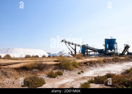 Salt production, conveyor belt with marine salt produced by the evaporation of seawater. Stock Photo