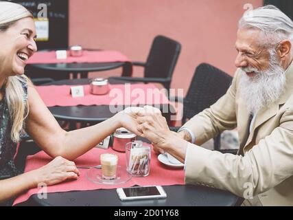 Happy senior couple drinking coffee in bar outdoor - Fashion mature husband and wife having tender moments together Stock Photo