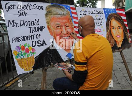 A man paints a poster of US President Donald Trump and first lady Melania Trump.President Donald Trump and first lady Melania have tested positive for the coronavirus ahead of the presidential election. Stock Photo