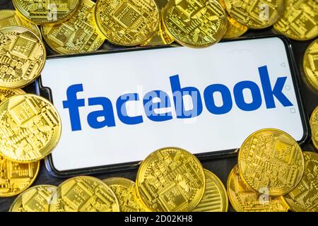 Bangkok, Thailand - July 2, 2019: Phone with Facebook logo on screen is placed with golden coins. Facebook reported to utilize new cryptocurrency Stock Photo