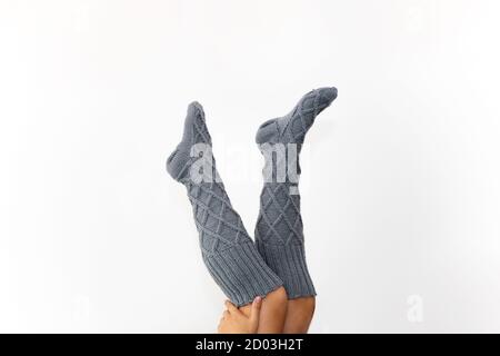 Gray knitted knee socks on the legs on a white background. Legs in long socks upside down. Hobby Stock Photo