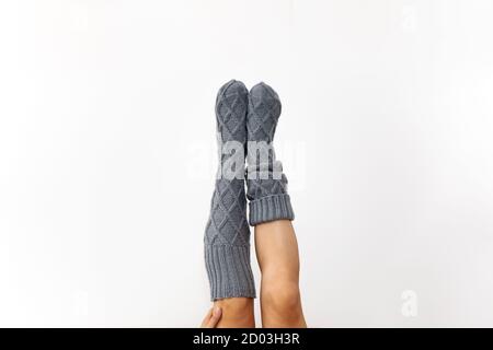 Gray knitted knee socks on the legs on a white background. Legs in long socks upside down. Hobby Stock Photo