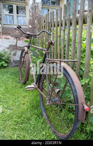 Old rusty bicycle leaning against a wooden fence Stock Photo