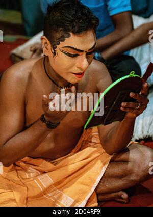 Munnar, India, Mar 11, 2018 - Traditional Indian dancer applies paint to his face prior to show Stock Photo