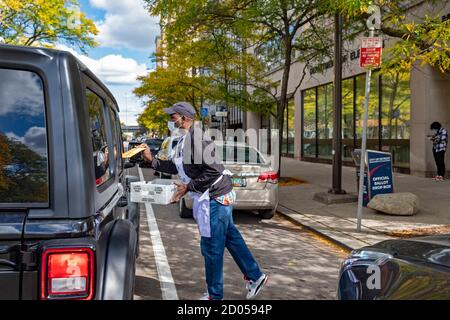 Detroit, Michigan, USA. 2nd Oct, 2020. A worker for Detroit's elections department accepts absentee ballots for the November presidential election from a steady stream of drivers at the city clerk's office. Credit: Jim West/Alamy Live News Stock Photo