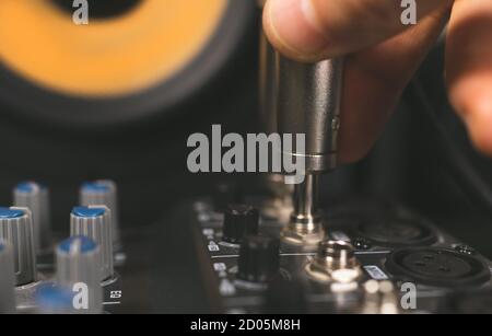 Sound engineer plugging jack audio cable on studio mixer. Stock Photo