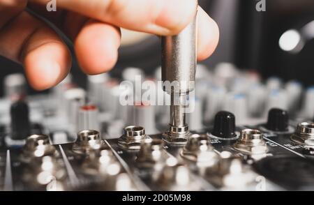 Sound engineer plugging jack audio cable on studio mixer. Stock Photo