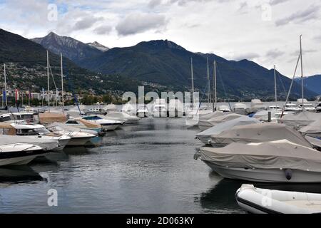 Sailing yachts arranged in row in marina covered for winter season and with lowered sails. The vessels anchor on Lake Maggiore in Locarno, Switzerland. Stock Photo