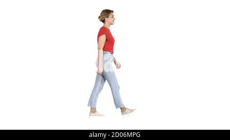 Woman in red t-shirt, jeans and sneakers walking on white backgr Stock Photo