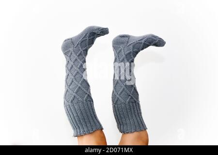 Gray knitted knee socks on the legs on a white background. Legs in long socks upside down. Hobby Stock Photo