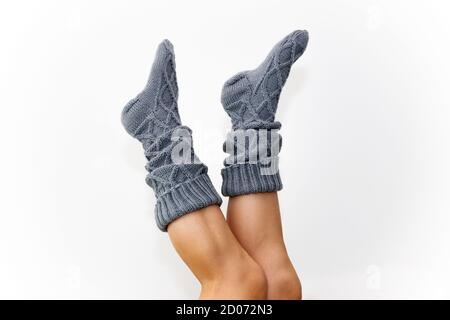 Gray knitted knee socks on the legs on a white background. Legs in long socks upside down. Hobby Stock Photo