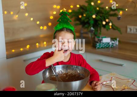 Happy little girl prepares cookies on the eve of christmas. A child in the kitchen waiting for the new year. Stock Photo