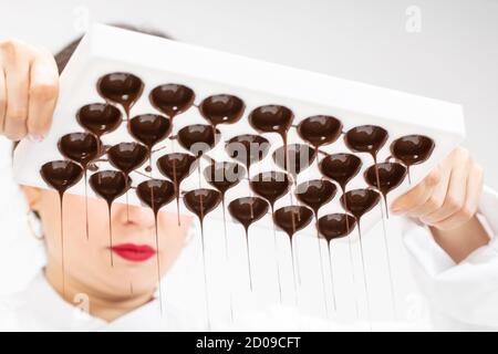 chocolatier pouring excess melted dark chocolate from molds preparing candy