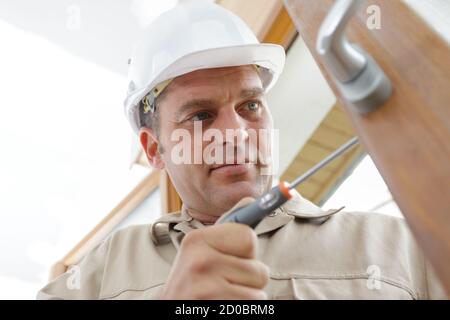 service man installing window with screwdriver Stock Photo