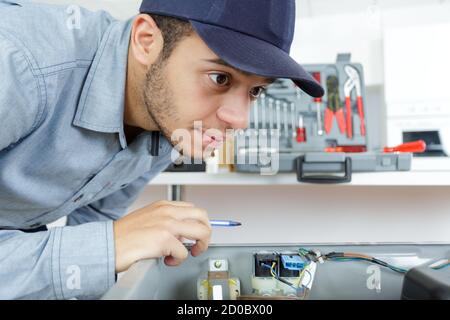 young repairman fixing and repairing a machine Stock Photo