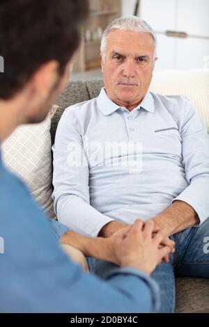 handsome man looking at sad senior dad Stock Photo