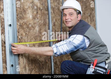 young man measures a warmed wall Stock Photo