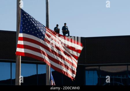 Police keep watch with a flag still at half-staff at the second court appearance of James Holmes, in Centennial, Colorado July 30, 2012. The former graduate student accused of killing 12 people in a shooting spree at a Denver-area movie house was due to make a second court appearance on Monday as prosecutors and defense lawyers sparred over a mysterious package sent to his psychiatrist.  James Holmes, 24, was arrested shortly after prosecutors say he opened fire at a packed midnight movie premiere of 'A Dark Knight Rises' on July 20.  REUTERS/Rick Wilking (UNITED STATES - Tags: DISASTER POLITI
