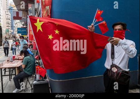 Hong Kong, Kowloon, China. 1st Oct, 2020. A pro-China supporter gives away Chinese flags and balloons to pedestrians in Hong Kong, China, on October 1, 2020. Police deployed 6,000 officers during 71st China's National Day anniversary to counter any illegal protests and assemblies in Hong Kong. Credit: Miguel Candela/SOPA Images/ZUMA Wire/Alamy Live News Stock Photo