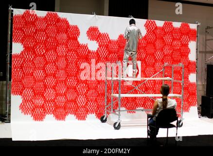 Japanese artist Sasaki paints the individual heartbeats of attendees at the Dwell on Design show in Los Angeles, California June 26, 2011. Sasaki is collecting donations for tsunami victims in Japan. After making a donation, the attendee's pulse is electronically monitored and relayed by speaker to the artist, who then interprets the beats onto a canvas using red paint.  REUTERS/Mike Blake  (UNITED STATES - Tags: SOCIETY)