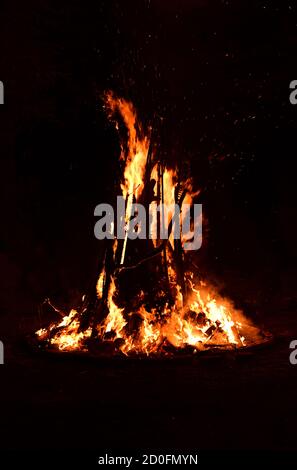 Isolated image of a bonfire with speckles of flames blowing in the air in the dark Stock Photo