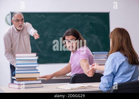 Old teacher and two students in the classroom Stock Photo