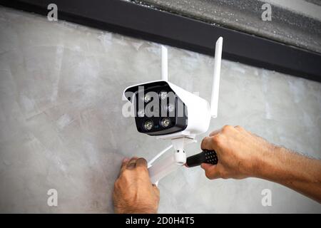 Technicians are installing wireless CCTV cameras on the walls of the house for security purposes. Stock Photo