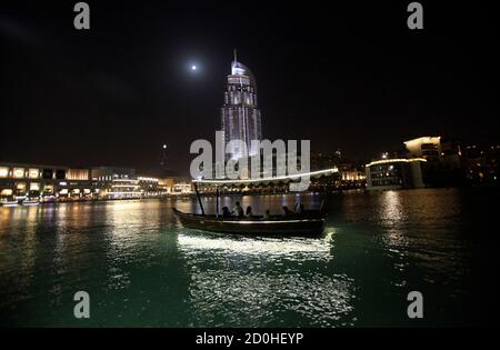 People ride a boat on an artificial lake at the Dubai Mall area in Dubai March 15, 2014. Dubai's Emaar Properties said it would sell up to 25 percent of its shopping mall and retailing unit in a public offer expected to raise 8 to 9 billion dirhams ($2.18-$2.45 billion), making it one of the region's largest equity offers since 2008. Dubai-listed Emaar's flagship mall is the Dubai Mall, one of the largest in the world, which it says attracted more than 75 million visitors in 2013. The company also built the Burj Khalifa in Dubai, the world's tallest building. REUTERS/Saleh Salem (UNITED ARAB E