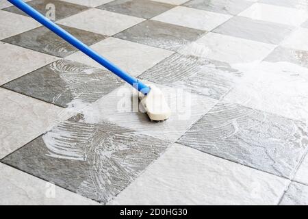 Clean the tile floor with a long-handled floor brush. Stock Photo