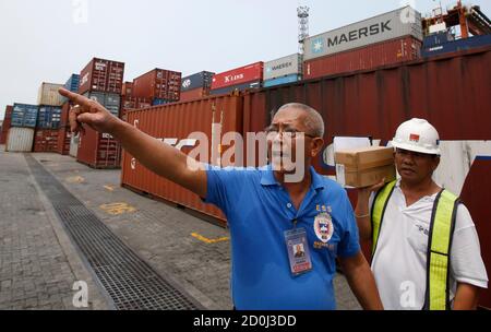 Stoel de begeleiding Puur A Bureau of Customs policeman (L) stands in front of containers containing  imported rice at the Manila International Container Port in Manila  September 24, 2014. Cargoes are being held up by severe