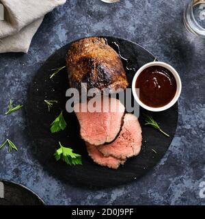 Close up of grilled beef on wooden board over stone background. Medium rare roast beef. Top view, flat lay Stock Photo