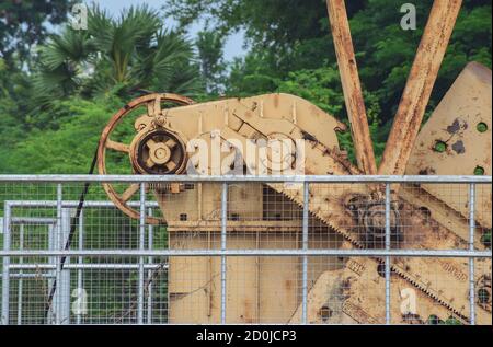 close-up of old rusty pump jack machinery extracting crude oil and natural gas from well in green oil field Stock Photo