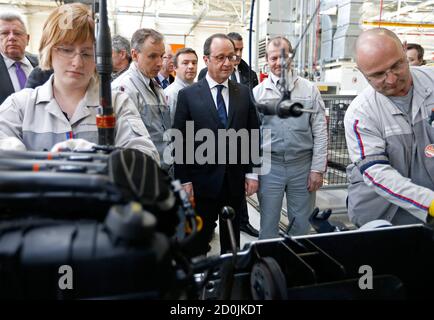 French President Francois Hollande (L) looks at workers as he visits the engines assembly line at the French carmaker PSA Peugeot Citroen engine factory in Tremery near Metz, North Eastern France, March 27, 2015. PSA Peugeot Citroen said on Friday it had chosen a French factory over a rival Spanish plant to expand engine production. The troubled carmaker said it will upgrade the Tremery site to produce the turbo version of a staple three-cylinder engine already manufactured there, safeguarding local jobs.  REUTERS/Vincent Kessler