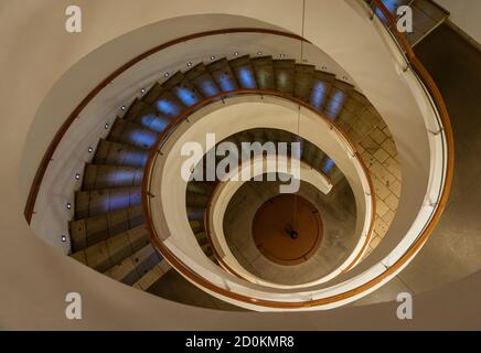 Spiral Staircase Leads Down Several Floors With Dramatic Lighting. Stock Photo